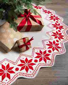 a christmas tree with presents on the floor next to it and a gift wrapped in red ribbon