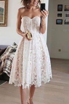 a woman in a white dress is taking a selfie with her cell phone while standing on the floor