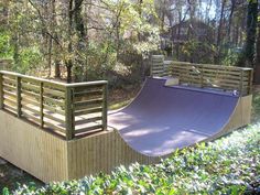 a skateboard ramp in the middle of a wooded area next to a wooden fence