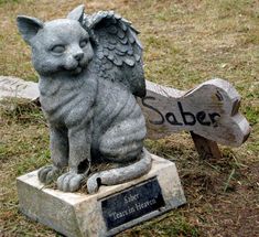 a statue of a cat sitting next to a wooden sign