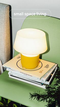 a yellow lamp sitting on top of a stack of books next to a green chair