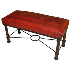 a red leather bench sitting on top of a metal frame with an animal design painted on it