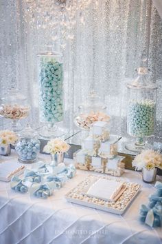 a table topped with lots of candy and candies next to a window covered in sequins