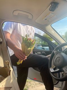 a man sitting in the driver's seat of a car holding flowers