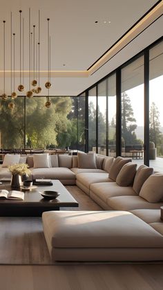 a living room with large couches, tables and lamps hanging from the ceiling in front of windows