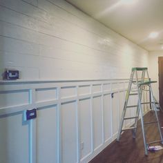 two ladders are in front of a white wall with wood planking on it