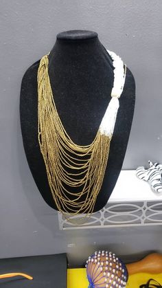 Handmade Kenyan Necklace.  Cascading beads in white and gold. Gorgeous statement piece. Gold Bib Necklace With Large Beads For Jewelry Making, White Beaded Chain Necklace Costume Jewelry, Gold Long Beaded Necklace With Large Beads, Gold Beaded Long Necklace With Large Beads, White Long Necklace With Dangling Beads, White Beaded Chain Costume Necklaces, Gold Bib Necklace With Large Beads As Gift, Gold Beaded Chain Bib Necklace As Gift, Gold Bib Necklace With Large Beads For Gift