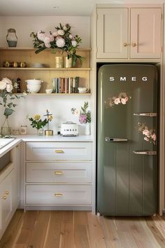 an old refrigerator is in the middle of a kitchen with white cabinets and wood floors