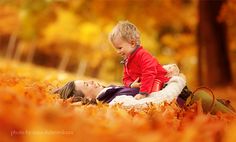 a woman laying on the ground next to a little boy who is sitting on top of her