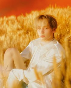 a boy sitting in the middle of a wheat field with his legs crossed and eyes closed