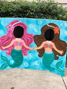 two little mermaids are holding hands in front of a blue box with bubbles on it