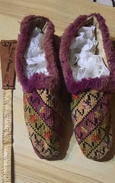 a pair of slippers sitting on top of a wooden table next to a ruler