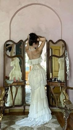 a woman standing in front of a mirror wearing a white dress with ruffles