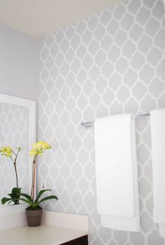 a bathroom with two white towels hanging on the wall and a flower in a pot