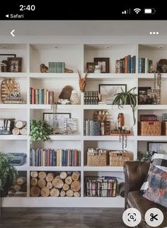 a living room filled with lots of books on top of a white book shelf next to a brown leather chair