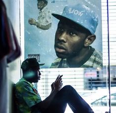 a man sitting in front of a window next to a poster