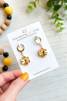 a pair of yellow and white flower earrings sitting on top of a table