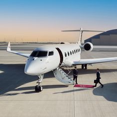 two men walking towards an airplane on the tarmac