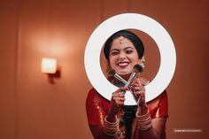 a woman holding a makeup brush in front of her face with a circular mirror behind her