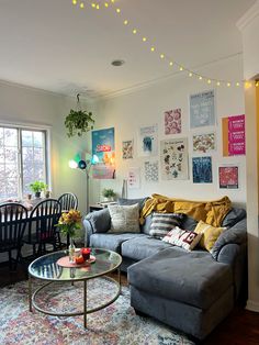 a living room filled with furniture next to a window covered in pictures and string lights