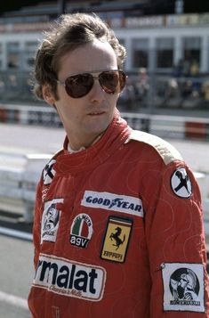 a man with sunglasses on standing in front of a race track