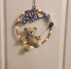 a crocheted teddy bear hanging from a string with lights on it's head