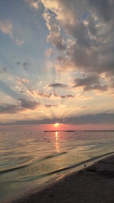 the sun is setting over the water at the beach