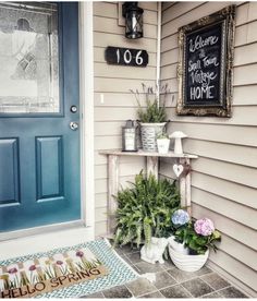 a blue front door with two potted plants and a welcome sign on the wall