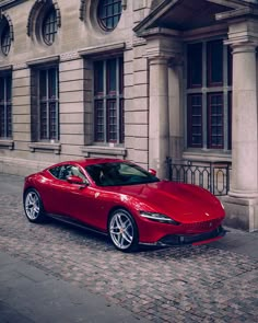 a red sports car parked in front of a large building on a cobblestone street