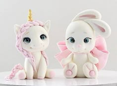 two white and pink figurines sitting next to each other on top of a table