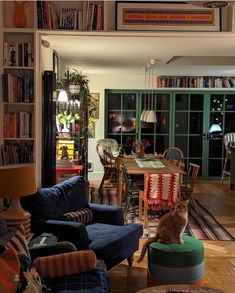 a living room filled with furniture and a cat sitting on top of a green ottoman