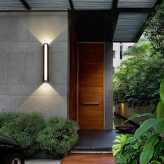 the entrance to a modern house with wooden door and light fixture on it's side