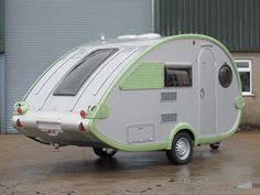 an rv is parked in front of a building with a garage door open and it's green trim