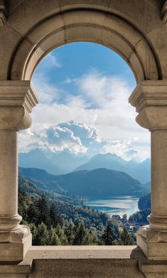 the view from an arch in a building overlooking mountains and trees, with water below