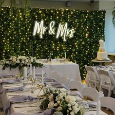 a table set up for a wedding reception in front of a green wall with mr and mrs written on it