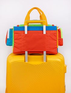 two pieces of luggage are stacked on top of each other, one is yellow and the other is red