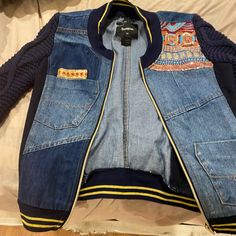 a denim jacket with an embroidered patch on the front and back, sitting on top of a bed