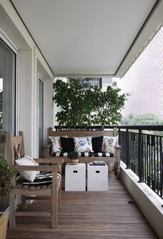 a balcony with two chairs and a table on top of the wooden floor next to a potted plant