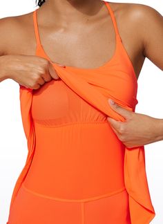 a woman in an orange swimsuit holding her shirt