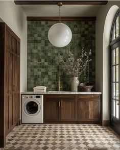 a washer and dryer in a room with green tiles on the wall behind it