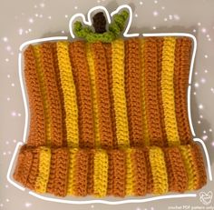 an orange and yellow crocheted dishcloth with a green leaf on the top