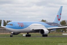 a blue and white jet airliner sitting on top of an airport runway with grass