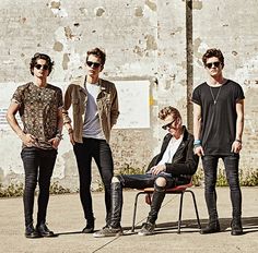 four young men standing and sitting in front of a building