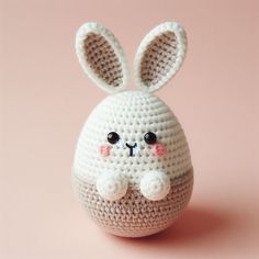 a crocheted white bunny sitting on top of a pink surface