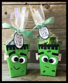 two green paper bags with faces on them