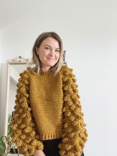 a woman standing in front of a mirror wearing a yellow sweater