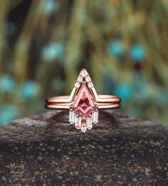 a pink diamond ring sitting on top of a rock