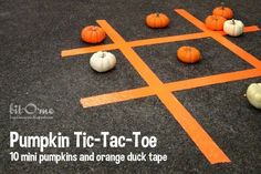 pumpkin tic - tac toe game on the ground with orange tape and white pumpkins