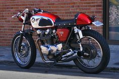 a red and black motorcycle parked on the side of a street next to a brick building