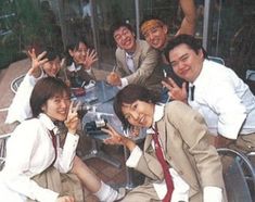 a group of people sitting around a table posing for the camera with their hands in the air